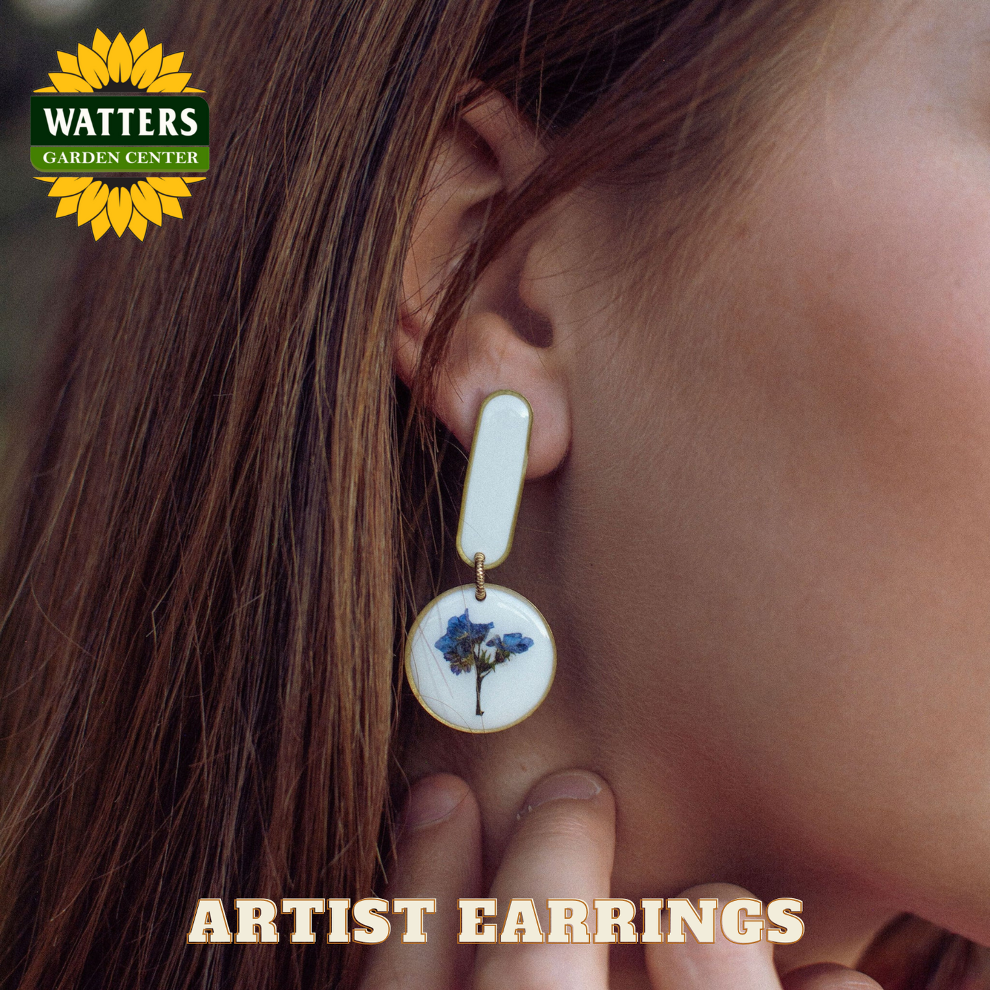 Close-up of a person wearing an earring with a floral design, branded with Watters Garden Center.