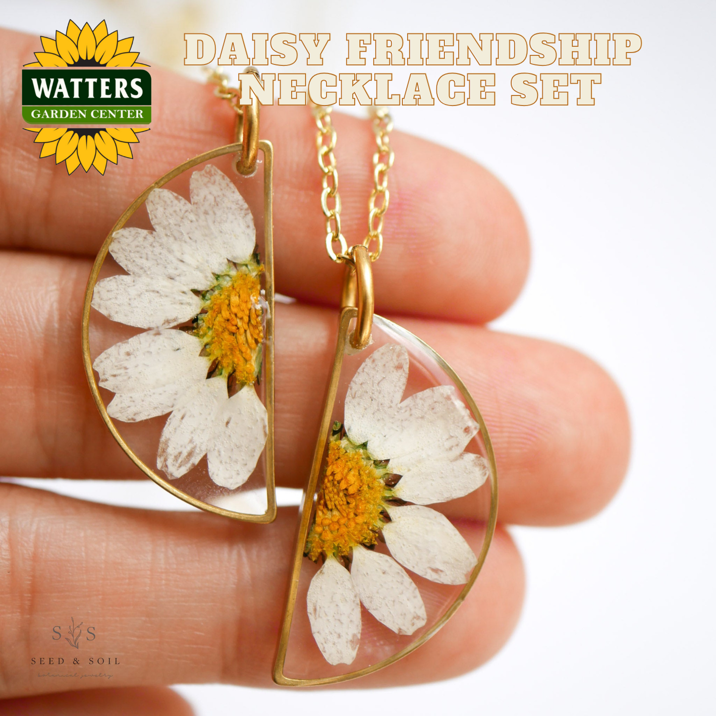 Daisy friendship necklace set held between fingers with Watters Garden Center logo.