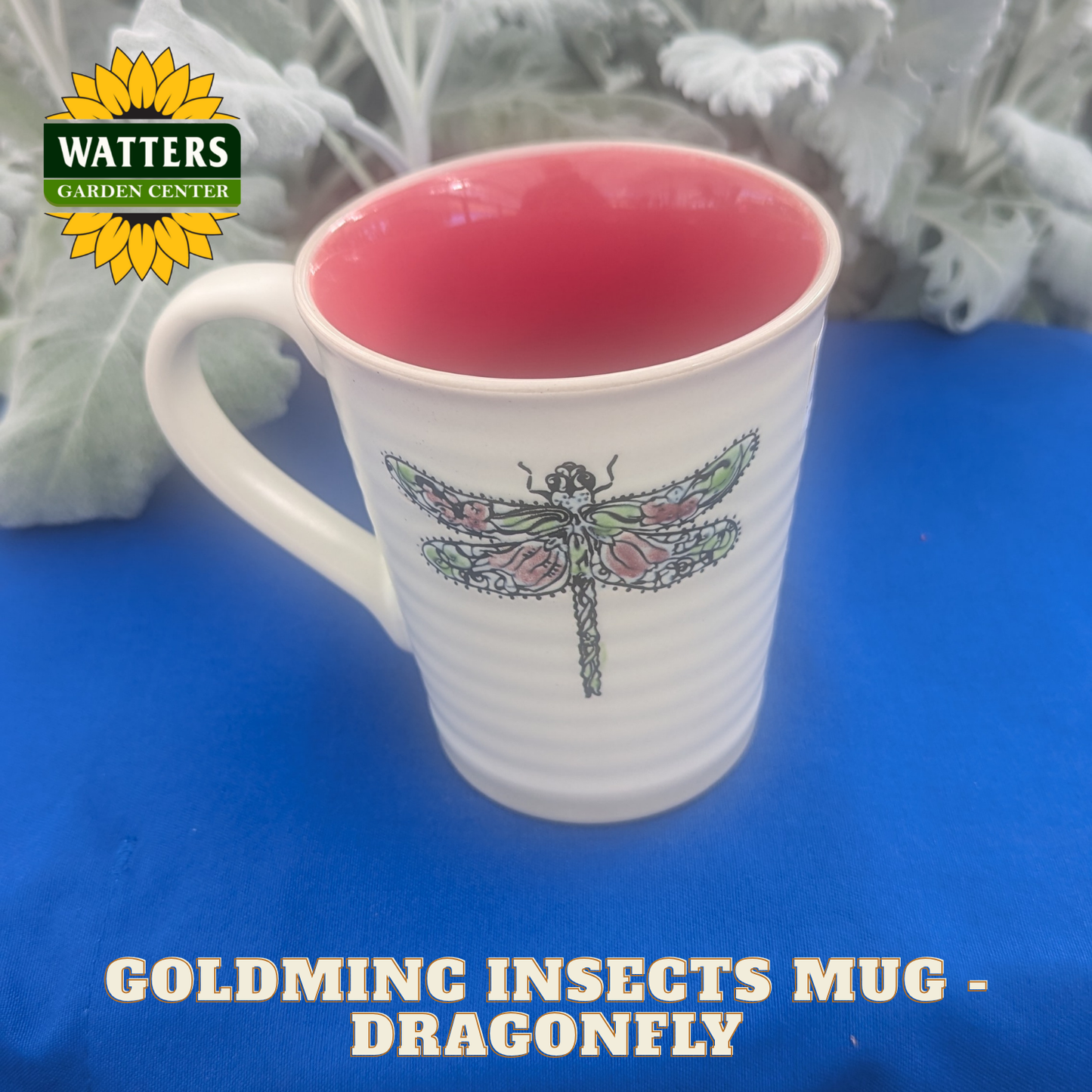White mug with dragonfly design on a blue surface, featuring Watters Garden Center logo.