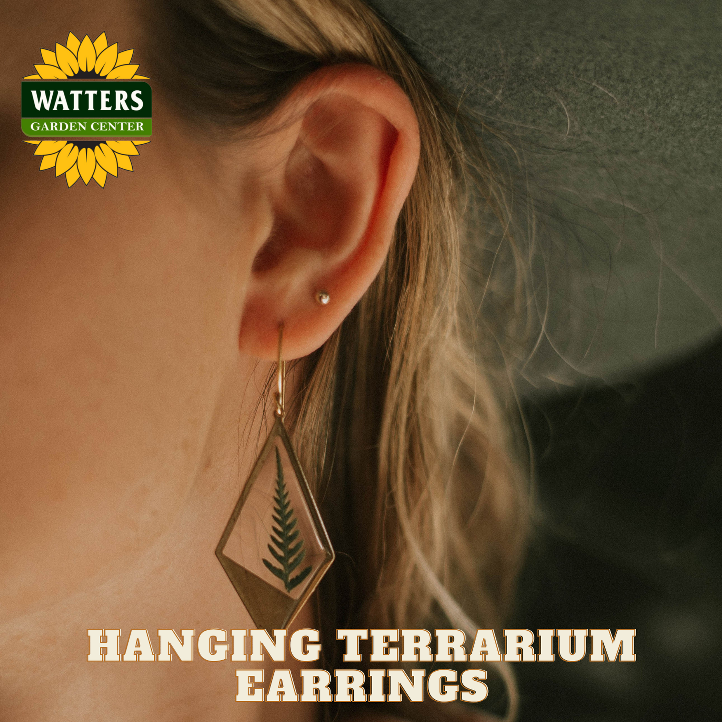 Hanging terrarium earrings worn by a person with Watters Garden Center logo.