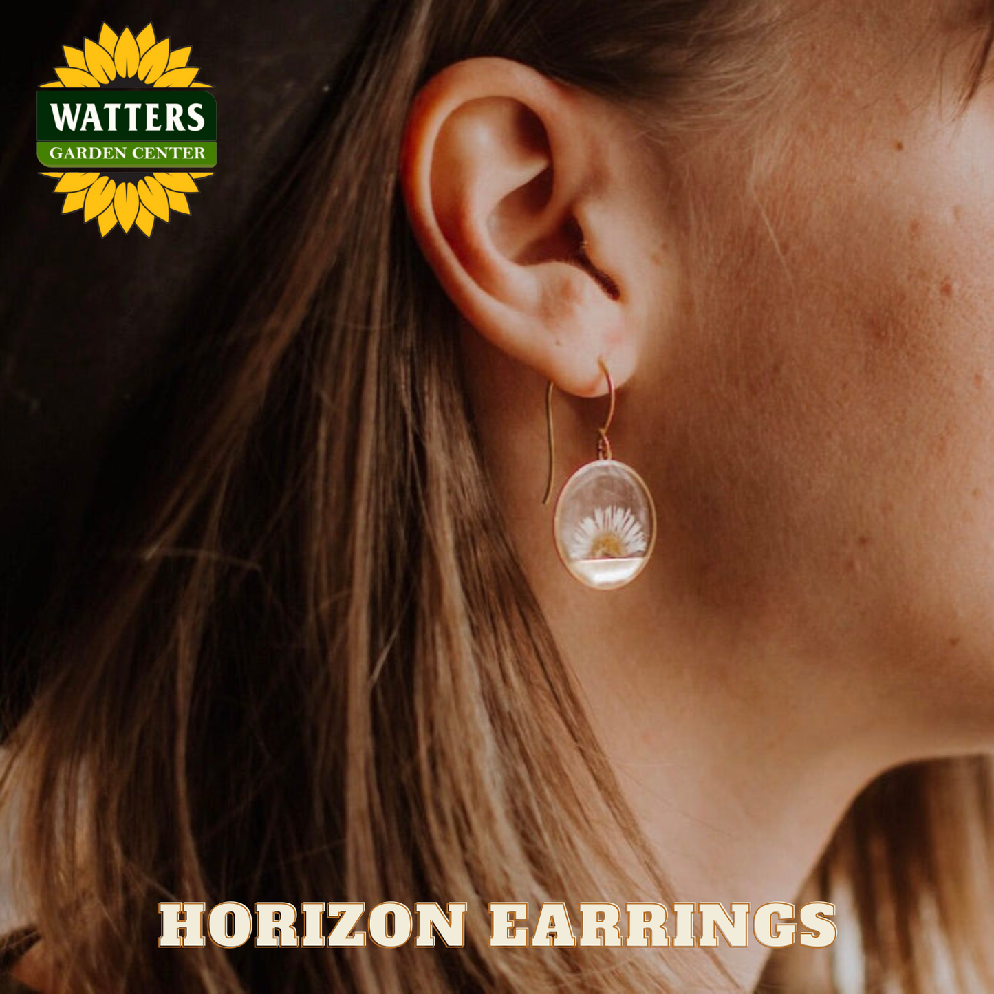 Close-up of an ear wearing a floral earring with Watters Garden Center logo.