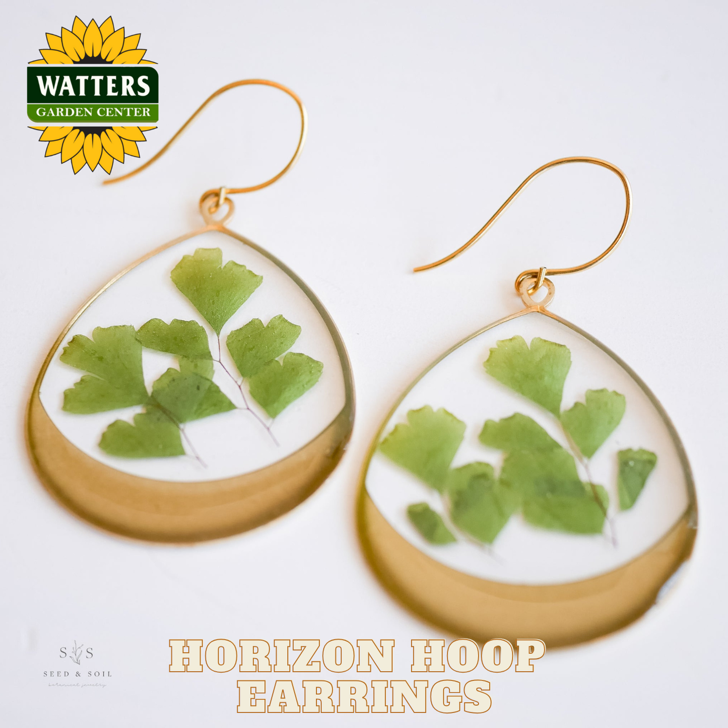 Horizon hoop earrings with green leaf design on a white background, featuring Watters Garden Center logo.