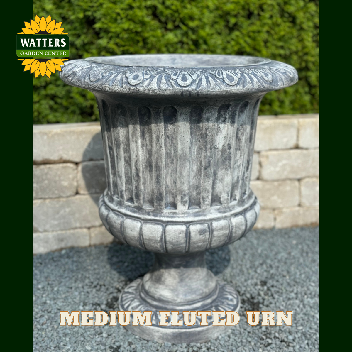 Fluted urn in a garden setting with Watters Branding.