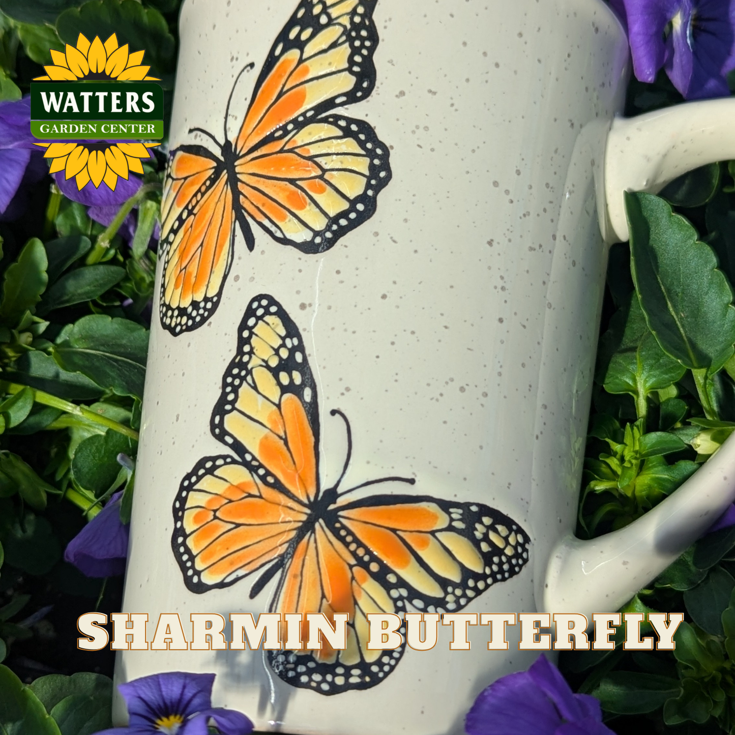 White mug with orange butterfly design surrounded by greenery and purple flowers, featuring Watters Garden Center logo.