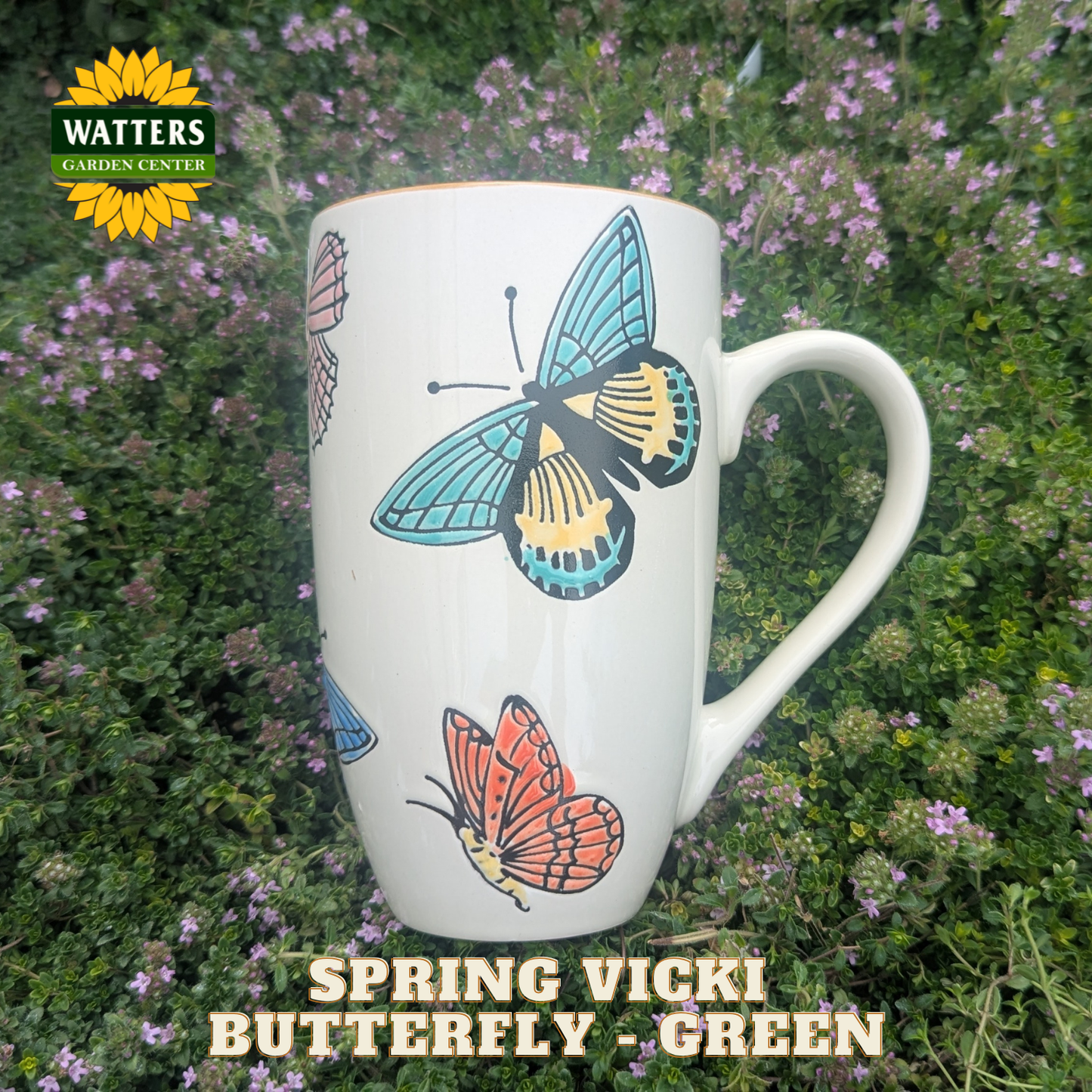 White mug with butterfly design on a background of greenery and flowers, featuring Watters Garden Center branding.