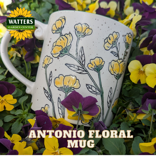 White mug with yellow floral design on a bed of purple and yellow flowers, featuring Watters Garden Center branding.