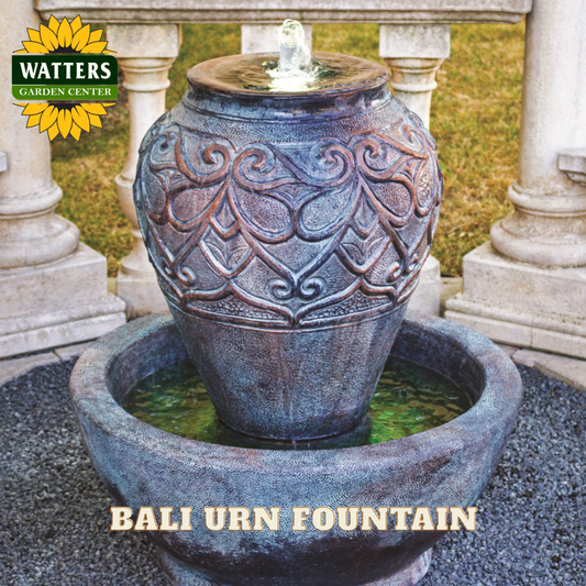 Decorative urn fountain with intricate patterns, set against a garden backdrop with 'Watters Garden Center' branding.