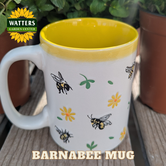 White mug with bee and flower design on a wooden surface, featuring Watters Garden Center logo.