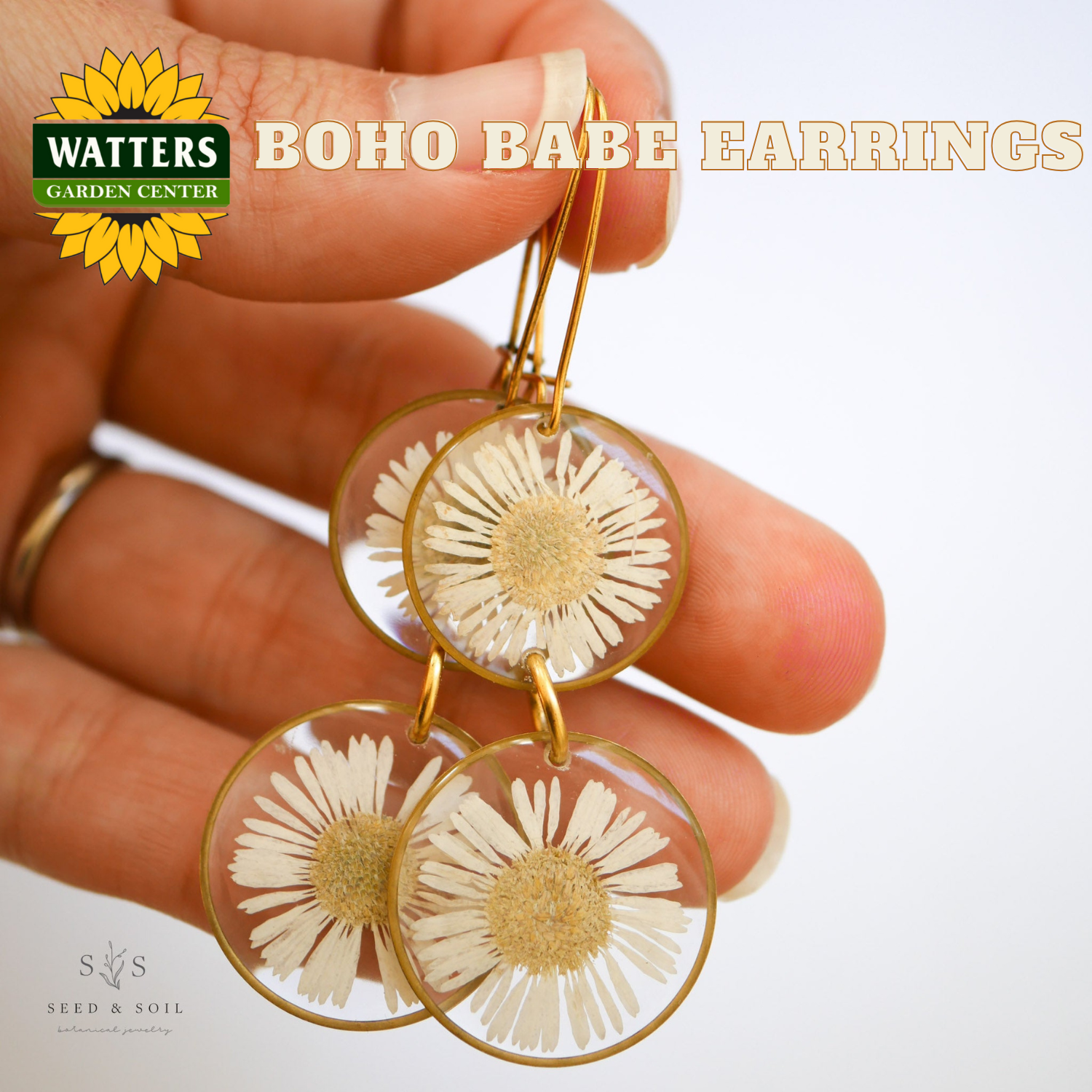 Hand holding boho babe earrings with Watters Garden Center logo.