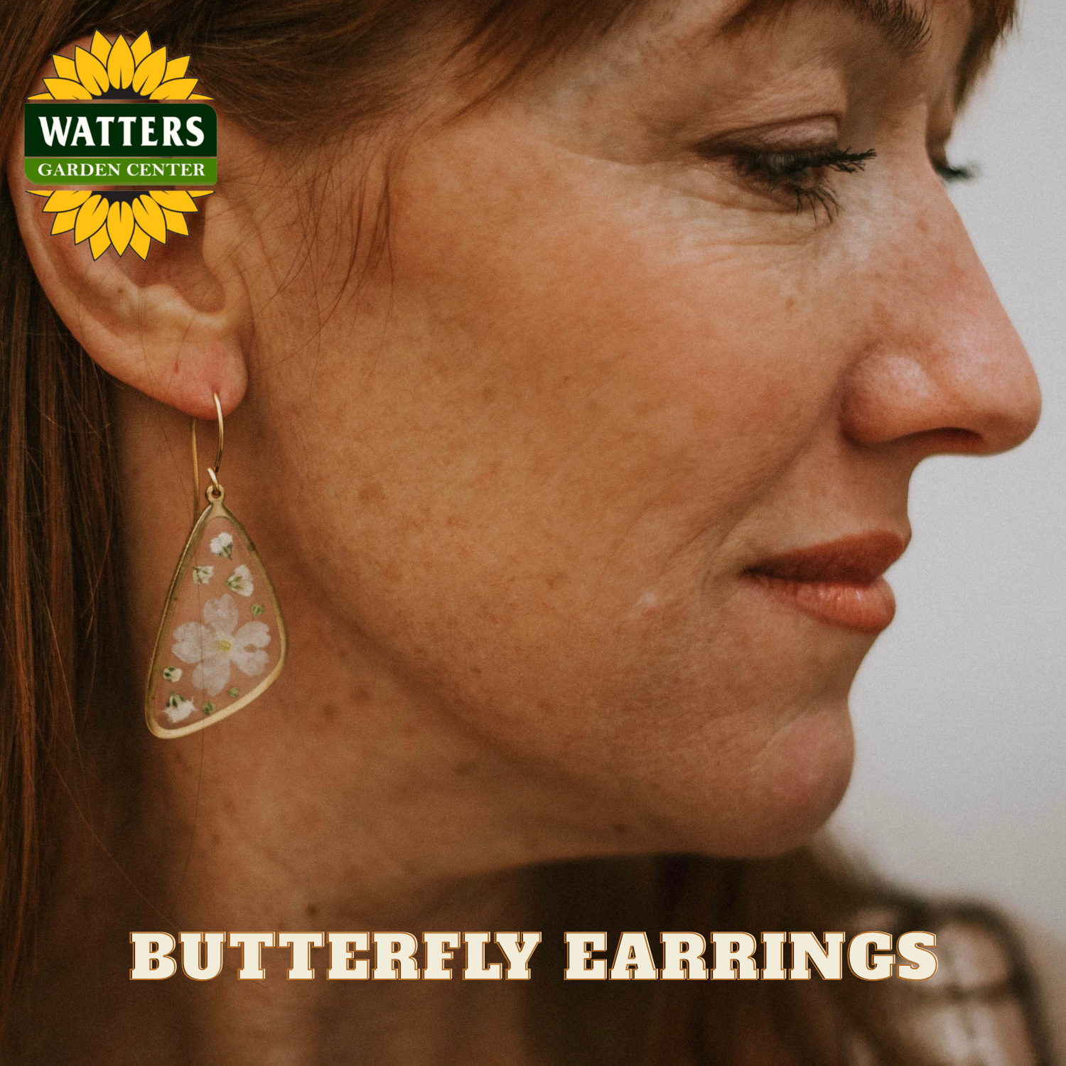 Close-up of a woman wearing butterfly earrings with Watters Garden Center logo.