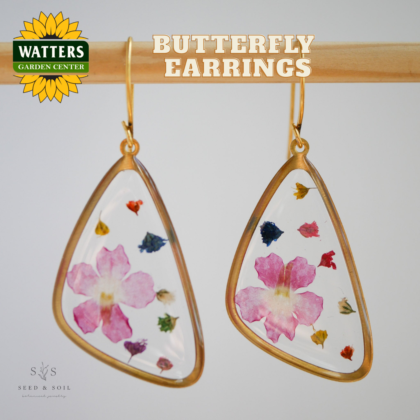 Butterfly earrings with floral design on a gray background, featuring Watters Garden Center logo.
