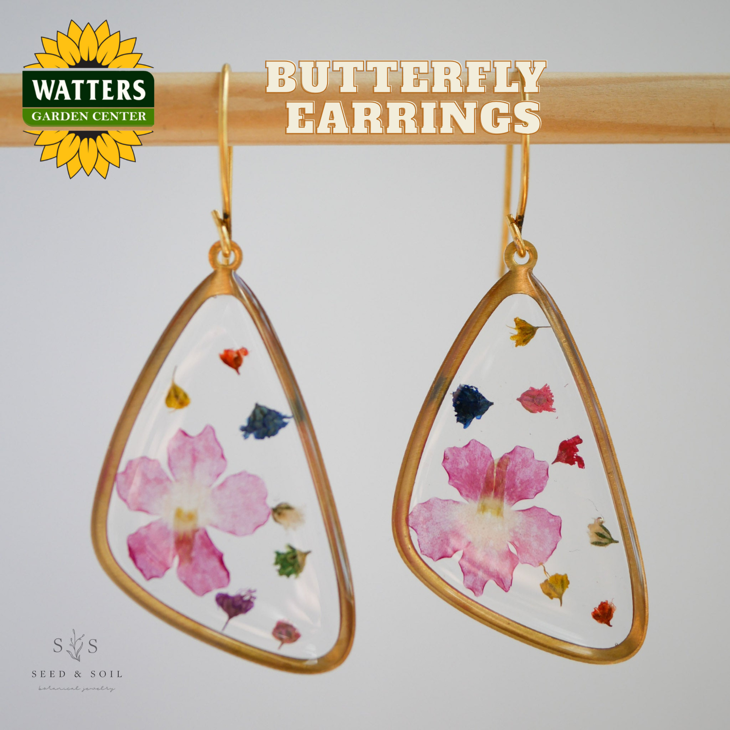 Butterfly earrings with floral design on a gray background, featuring Watters Garden Center logo.