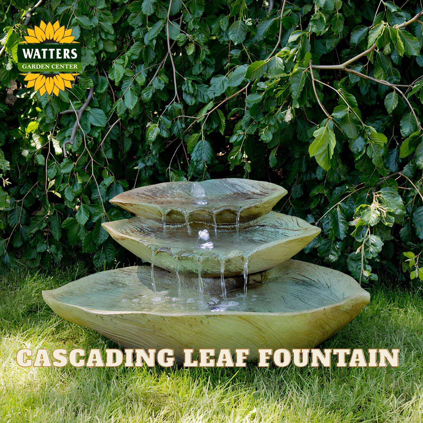 A three-tier cascading leaf fountain made of stone or resin, shown outdoors on grass with leafy green bushes behind it. Water flows from the top bowl to the middle and then to the bottom basin.