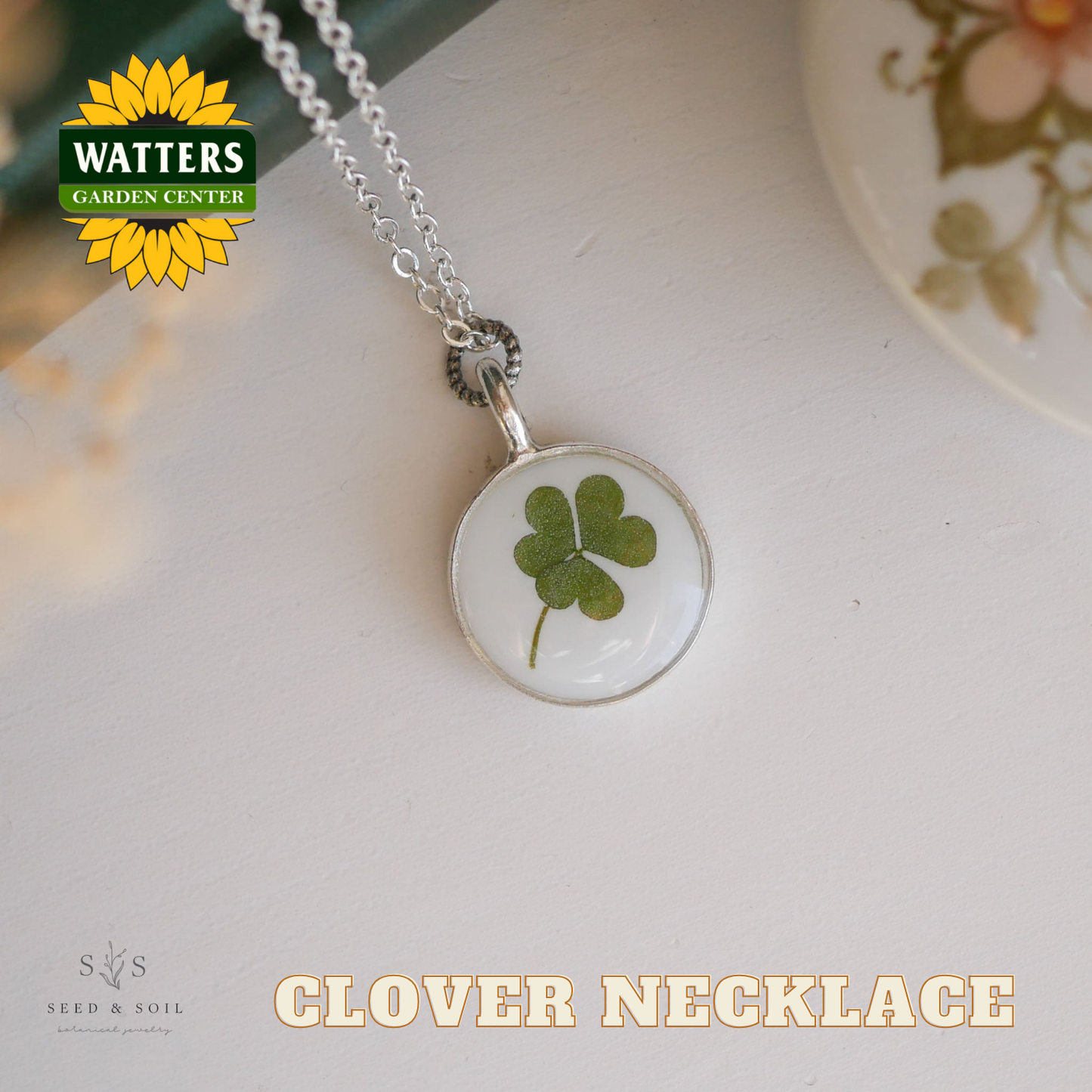 Clover necklace with Watters Garden Center logo on a white surface