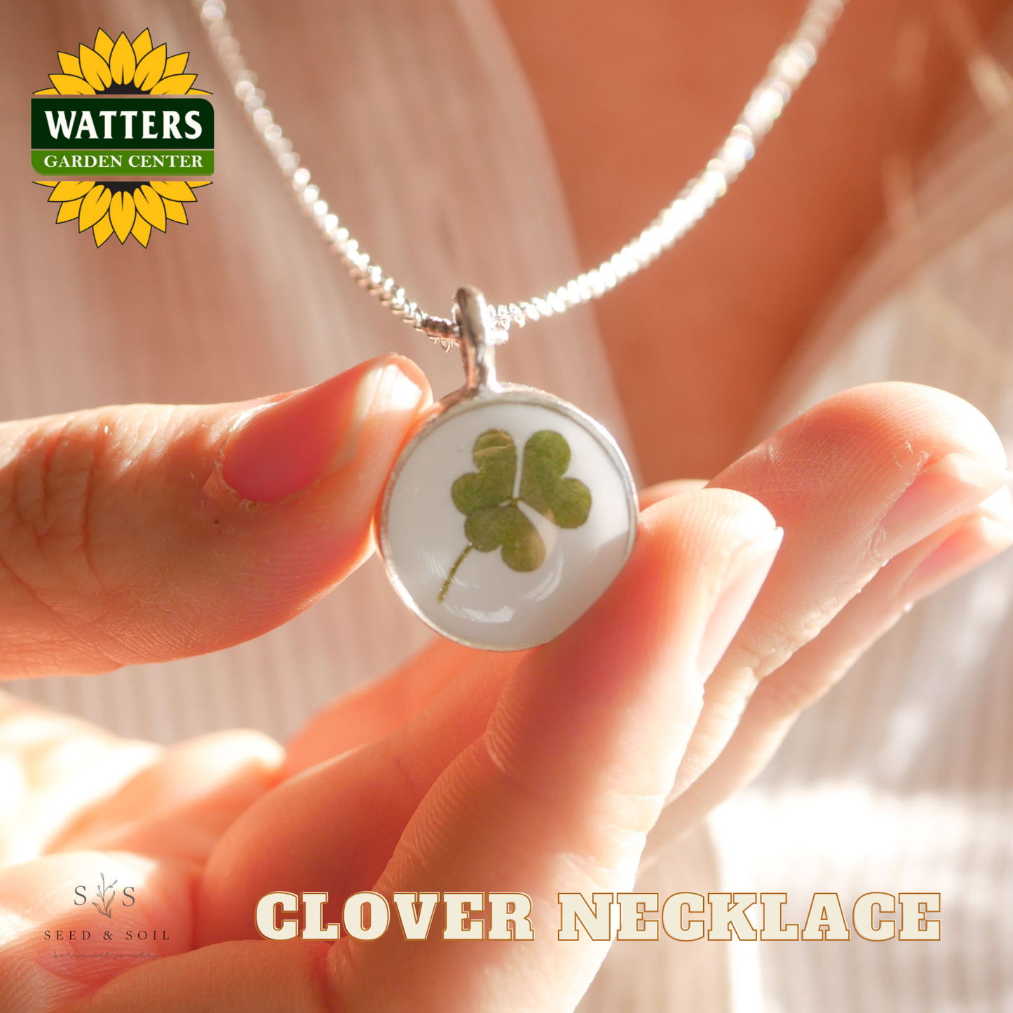 Clover necklace held by a hand with Watters Garden Center branding.
