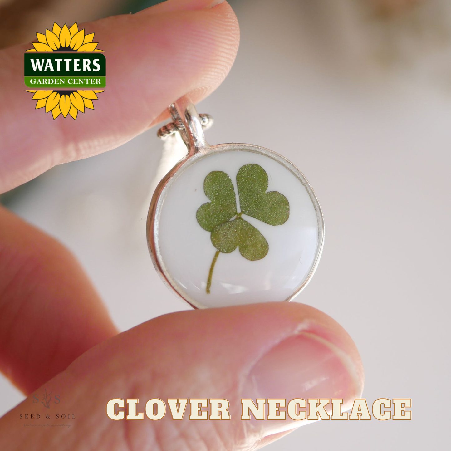 Clover necklace held between fingers with Watters Garden Center logo in the corner.
