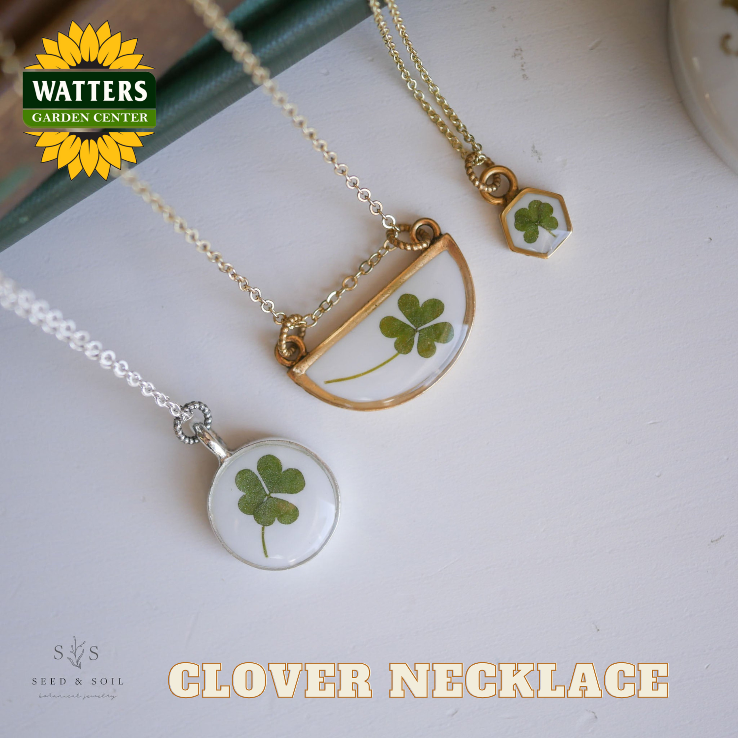 Three clover necklaces on a white surface with Watters Garden Center logo.
