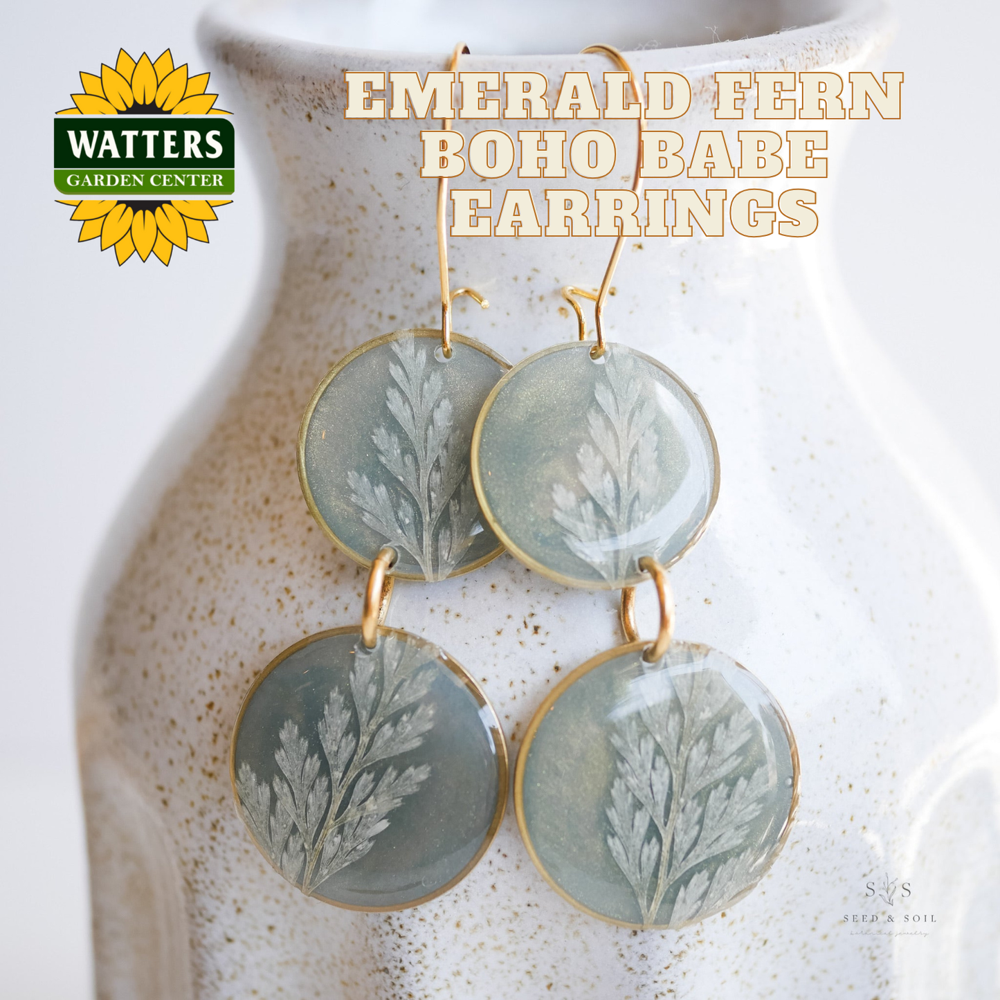 Earrings with fern design on a textured surface, featuring Watters Garden Center logo.