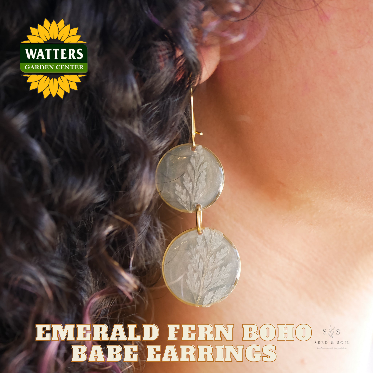 Close-up of a woman wearing emerald fern boho babe earrings with Watters Garden Center logo.