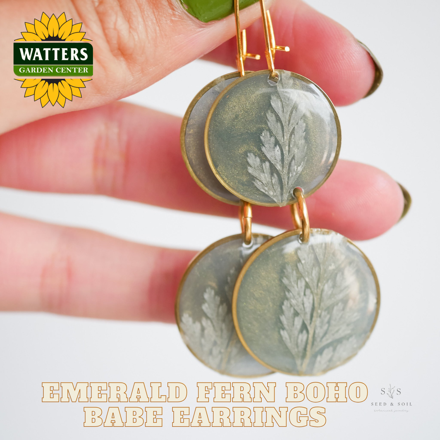 Earrings with green circular designs held by a hand, Watters Garden Center logo visible.