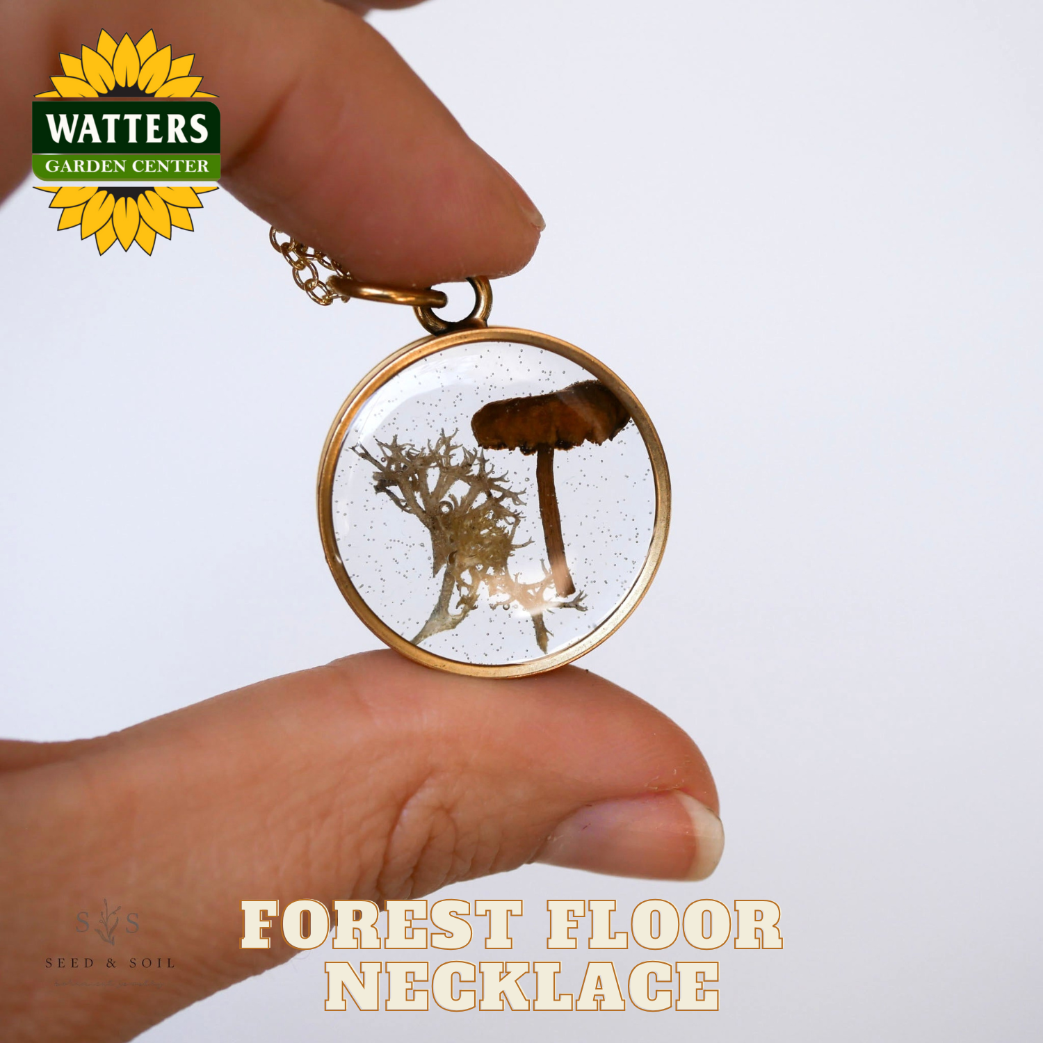 Hand holding a 'Forest Floor Necklace' with Watters Garden Center branding.