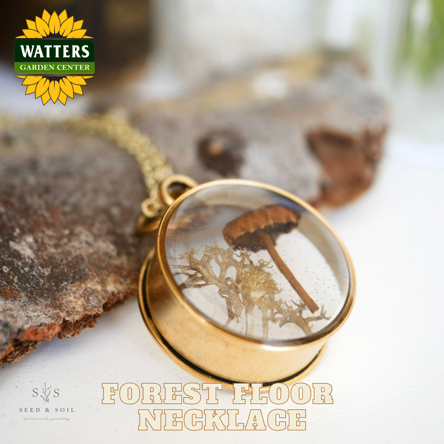 Gold necklace with a forest-themed pendant on a natural background, featuring Watters Garden Center logo.