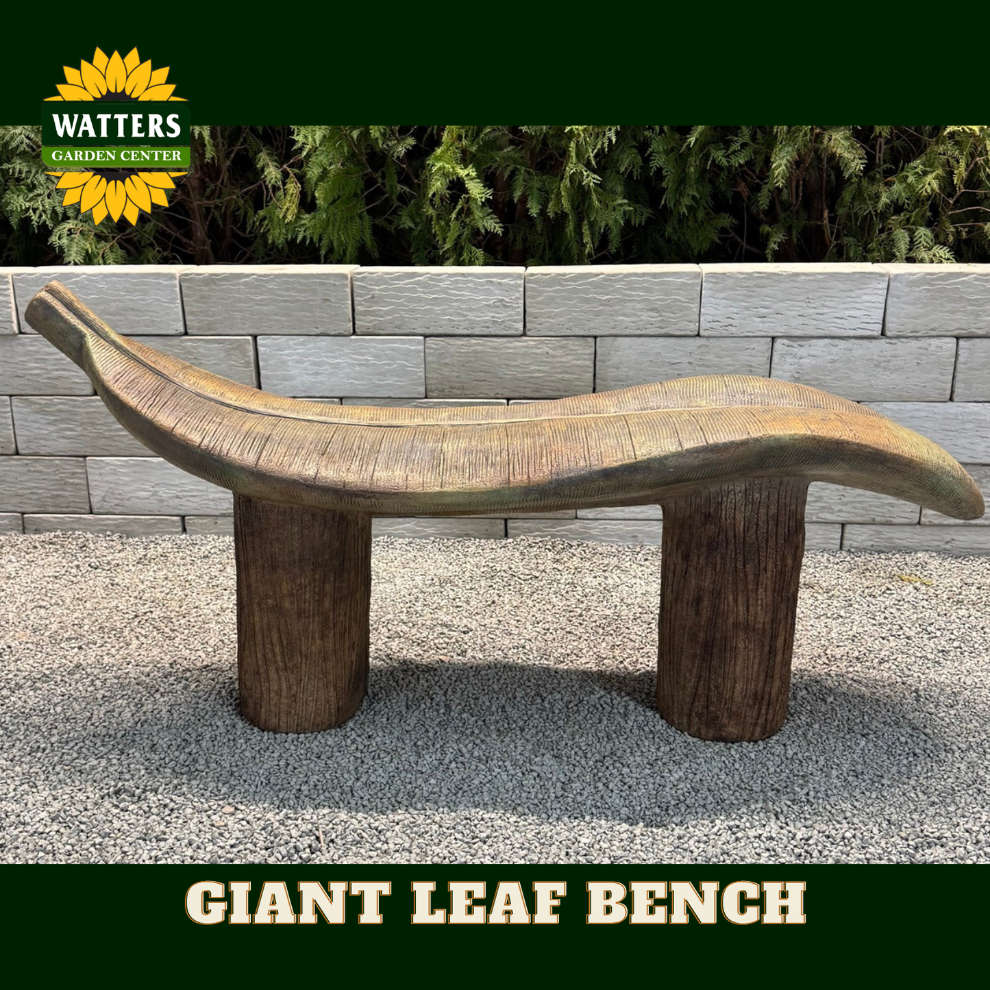 A giant leaf-shaped wooden garden bench with two log-style legs, shown outdoors on a gravel surface in front of a gray stone wall and green plants. The Watters Garden Center logo is visible in the top left, and 'GIANT LEAF BENCH' is written in a banner at the bottom.