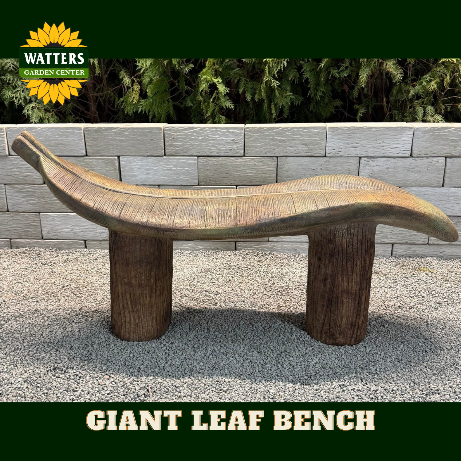 A giant leaf-shaped wooden garden bench with two log-style legs, shown outdoors on a gravel surface in front of a gray stone wall and green plants. The Watters Garden Center logo is visible in the top left, and 'GIANT LEAF BENCH' is written in a banner at the bottom.