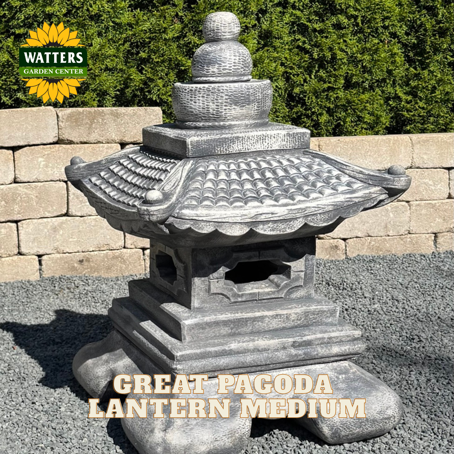 A gray stone-style pagoda lantern garden statue shown outdoors on gravel in front of a stone wall and green hedge. The Watters Garden Center logo appears in the top left, and the text 'GREAT PAGODA LANTERN MEDIUM' is overlaid at the bottom.