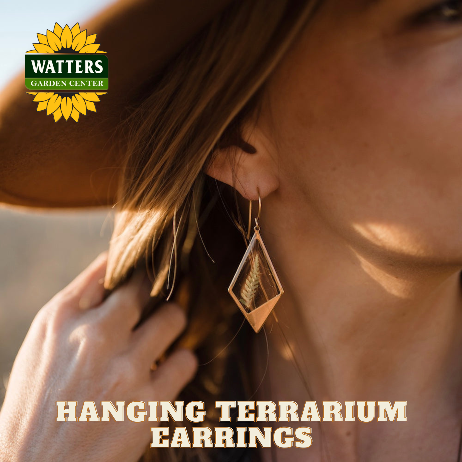 Woman wearing hanging terrarium earrings with Watters Garden Center logo.