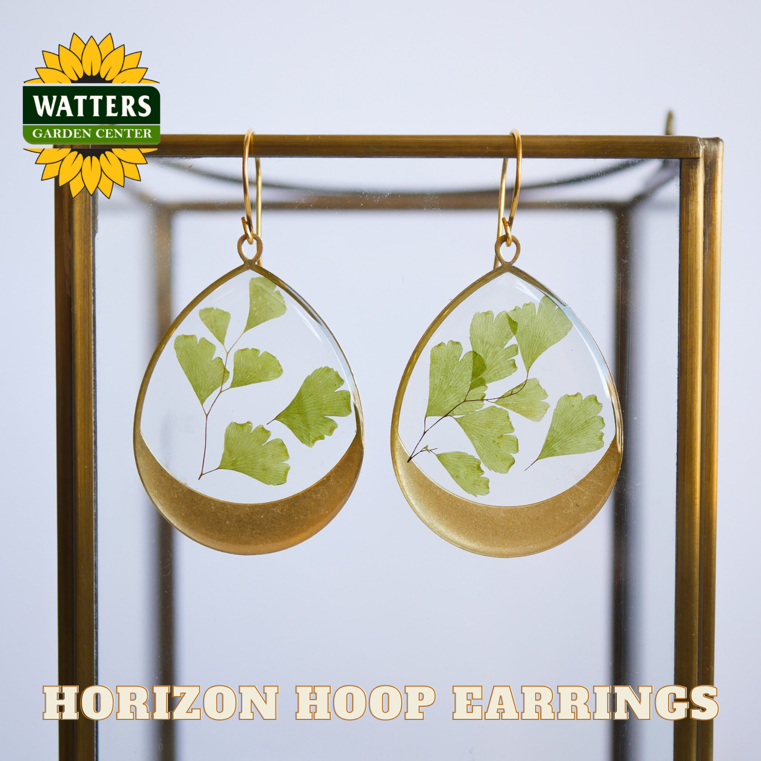 Teardrop-shaped earrings with green leaf design on a gold hoop, displayed against a white background with 'Watters Garden Center' branding.