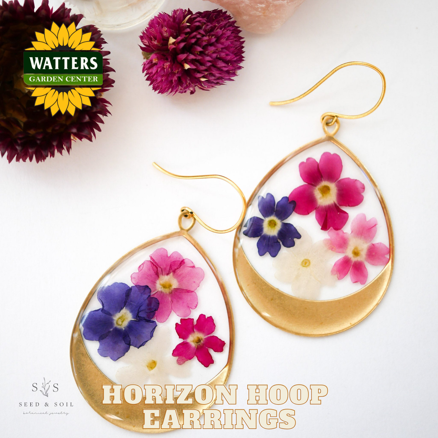 Gold hoop earrings with floral design on a white background, featuring Watters Garden Center logo.