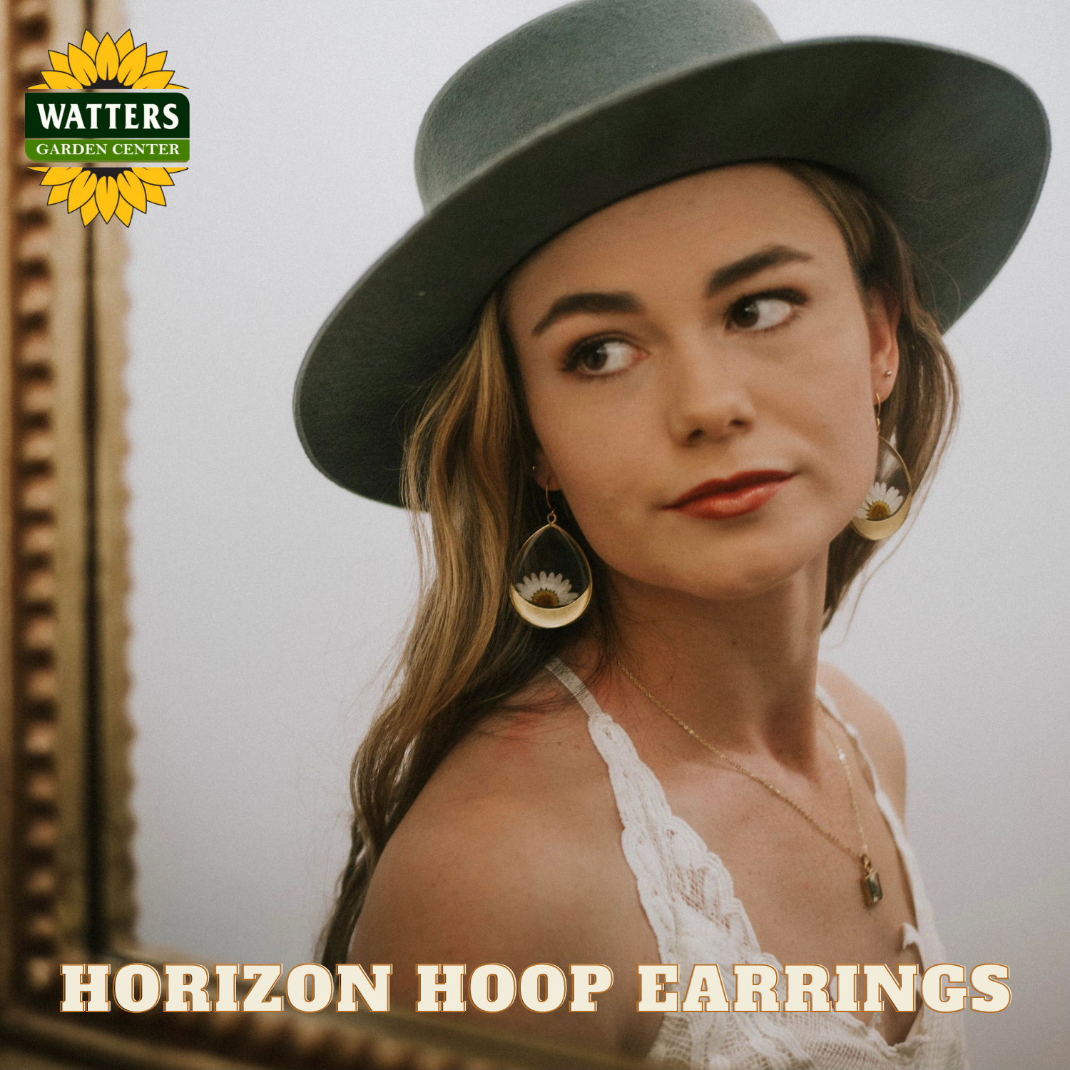 Woman wearing a green hat and hoop earrings with Watters Garden Center logo.