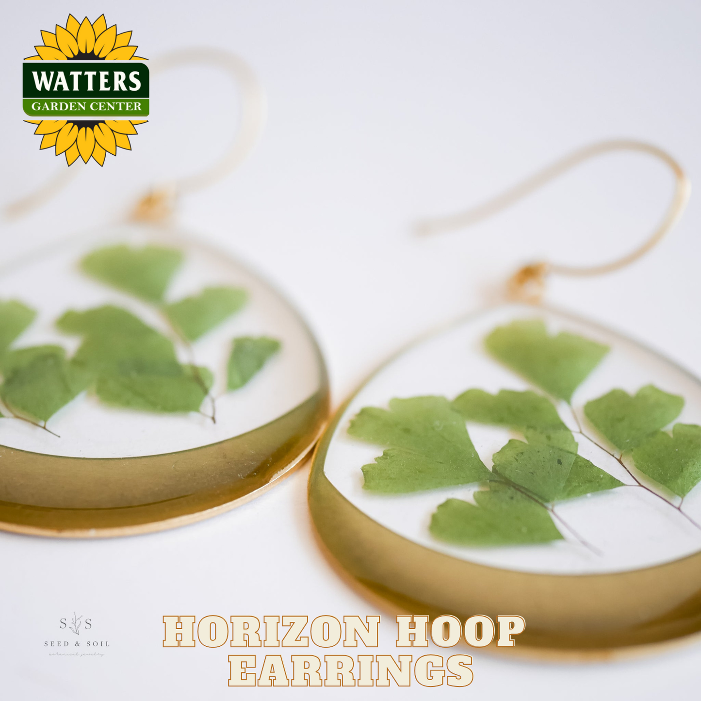 Horizon hoop earrings with green leaf design on a white background, featuring Watters Garden Center logo.
