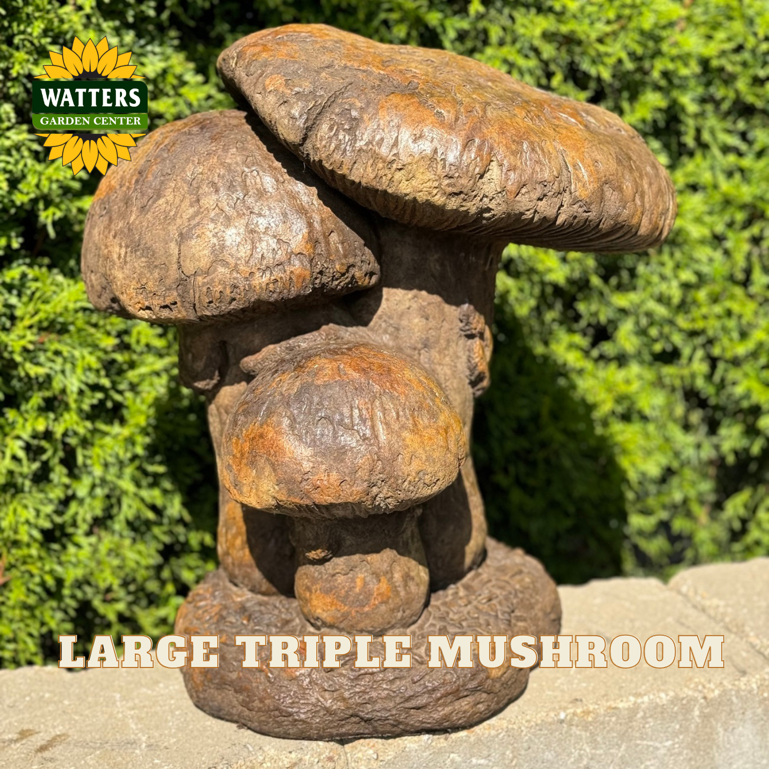 A large decorative garden sculpture shaped like three overlapping mushrooms, shown outdoors on a stone surface with green foliage in the background. The sculpture has a weathered rust-brown finish.