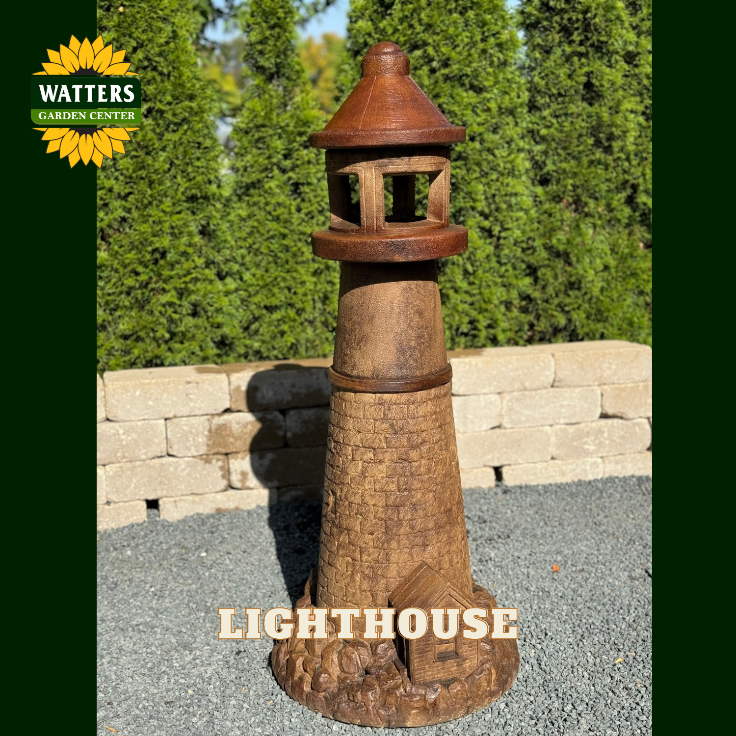 A rustic metal lighthouse garden stake with a weathered brown finish, shown outdoors on a gravel surface with a stone wall and green hedges in the background. The Watters Garden Center logo is visible in the top left corner, and the word 'LIGHTHOUSE' is written at the bottom.