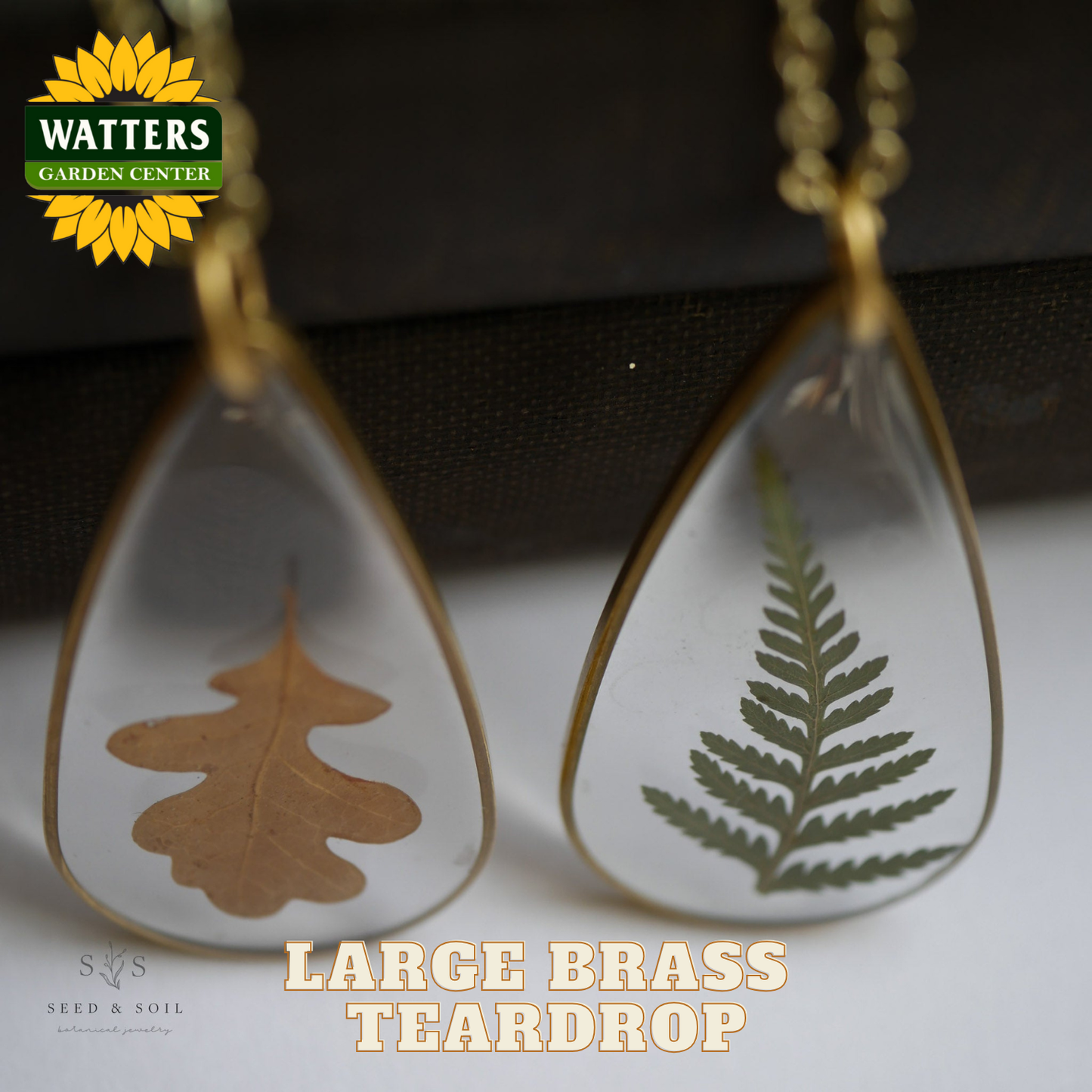 Two teardrop-shaped necklaces with leaf designs on a neutral background, featuring Watters Garden Center branding.