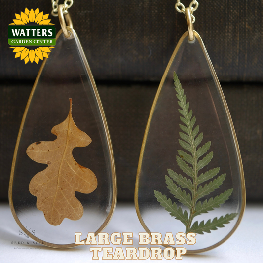 Two teardrop-shaped pendants with pressed leaves on a dark background, featuring Watters Garden Center branding.