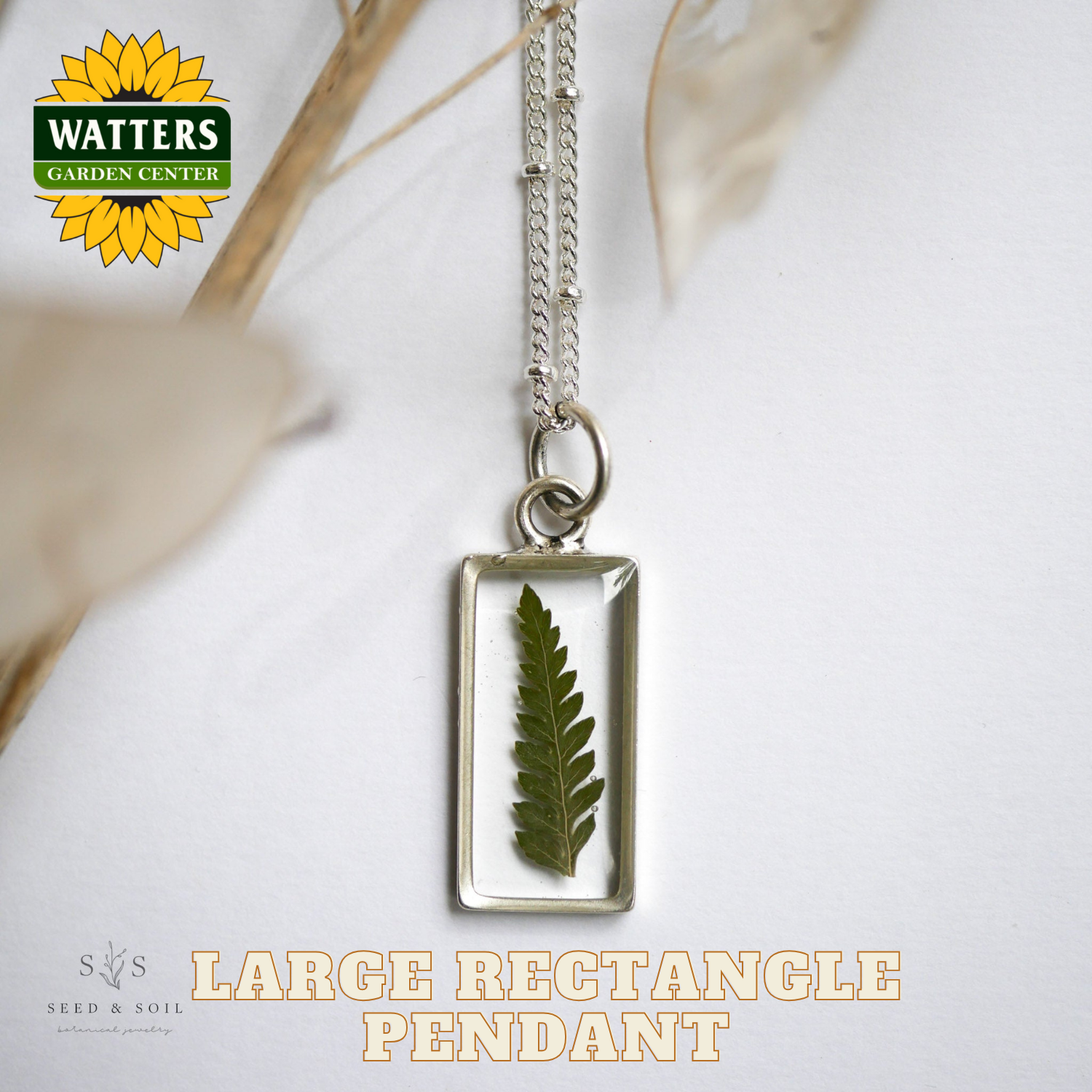 Necklace with a large rectangle pendant featuring a pressed leaf, branded with Watters Garden Center.