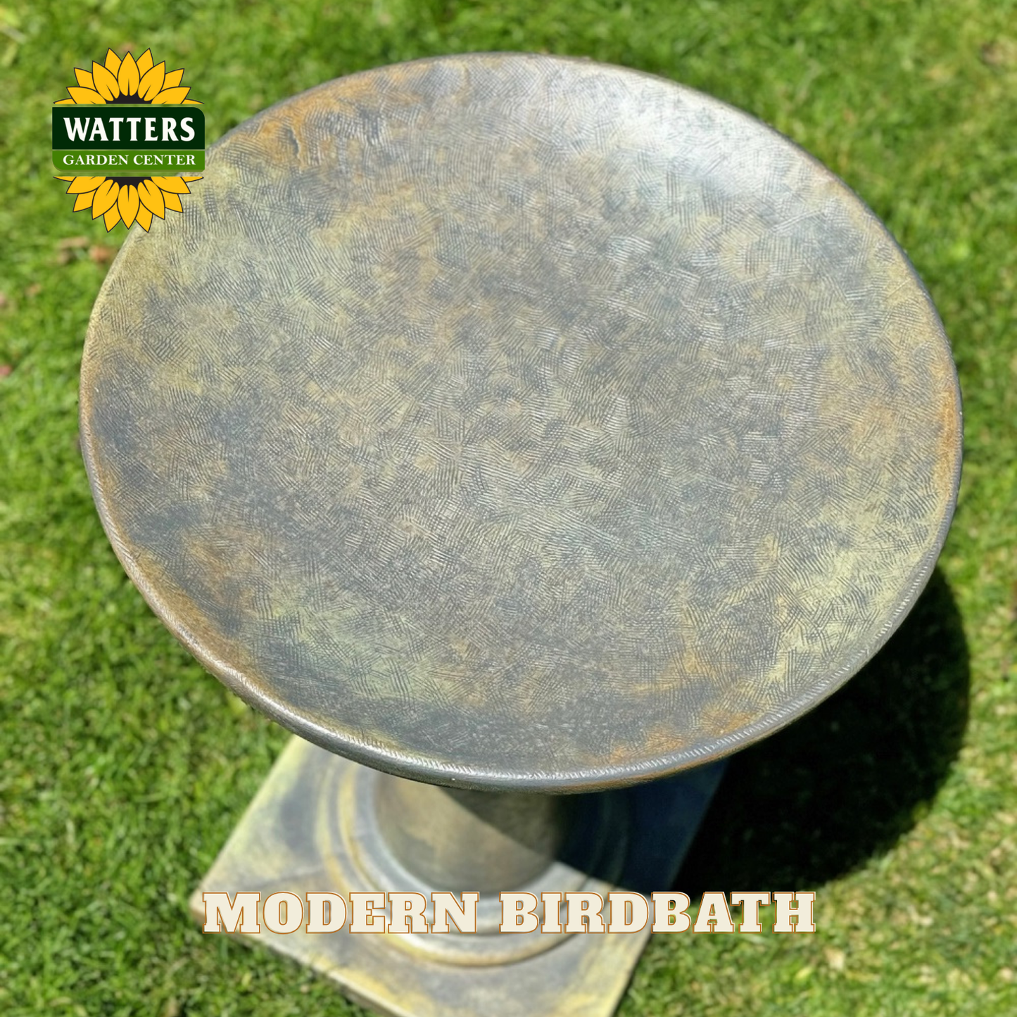 Round metal birdbath on grass with Watters Garden Center branding.