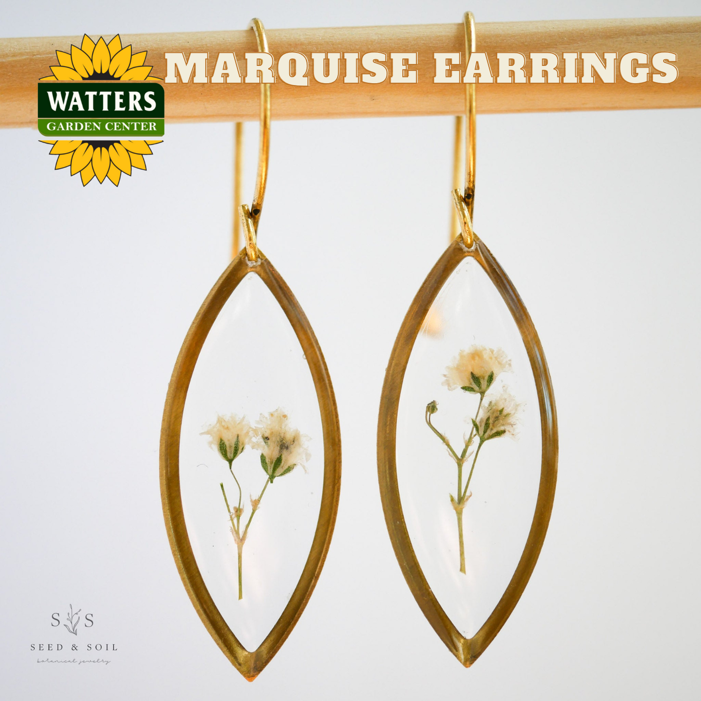 Marquise earrings with floral design hanging on a rod, branded with Watters Garden Center.