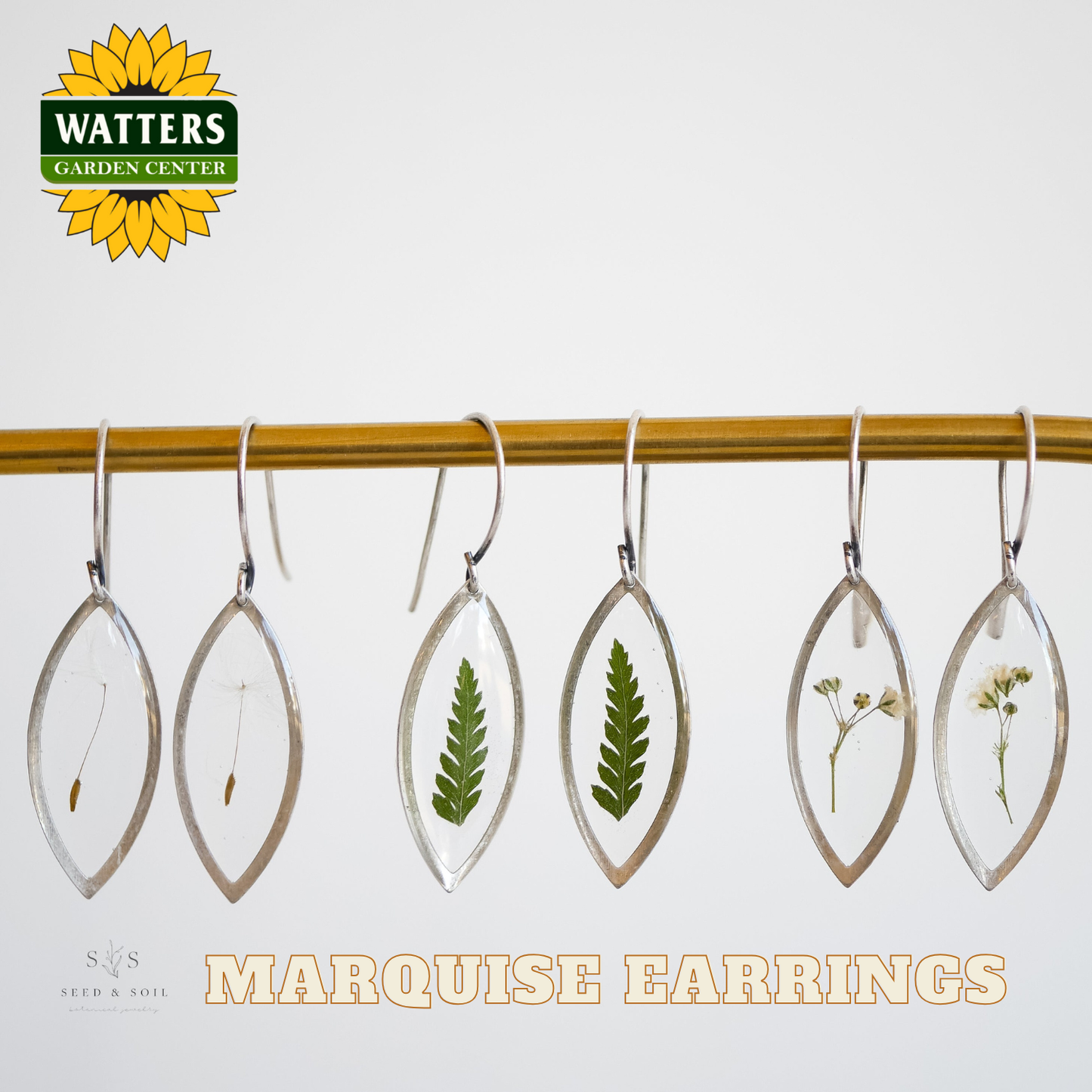 Marquise earrings with natural elements hanging on a rod, branded with Watters Garden Center.