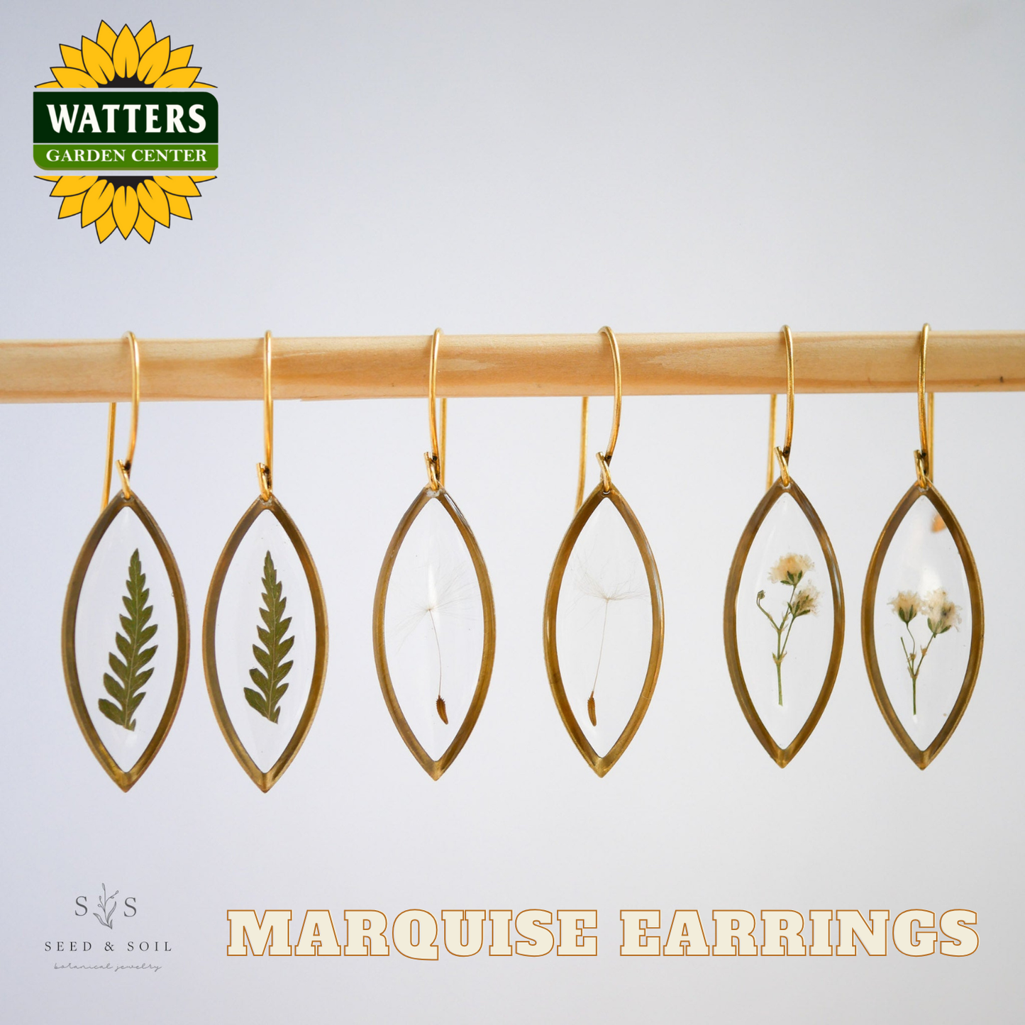 Marquise earrings with natural elements on a wooden rod, featuring Watters Garden Center branding.