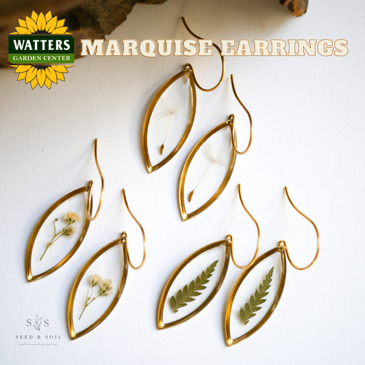 Gold marquise earrings with natural elements on a white background, featuring Watters Garden Center branding.