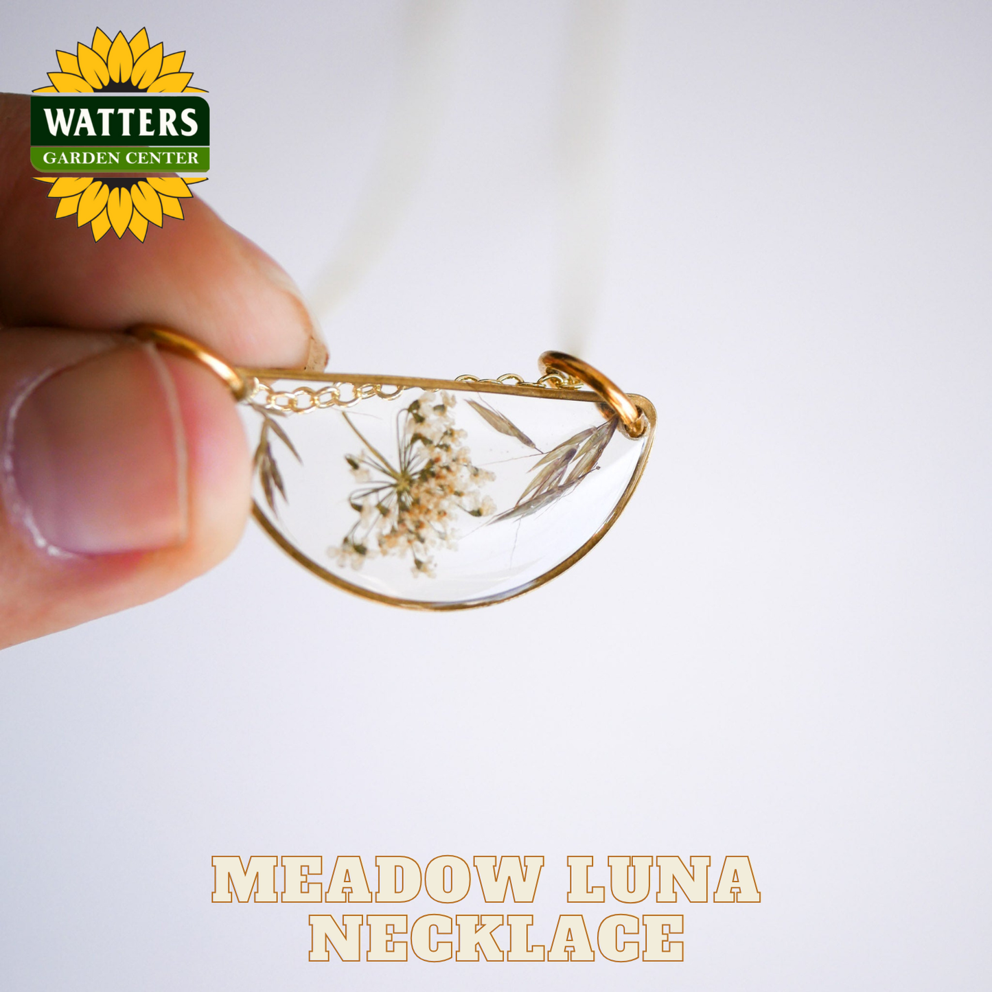 Gold necklace with dried flowers held by a hand, Watters Garden Center logo visible.