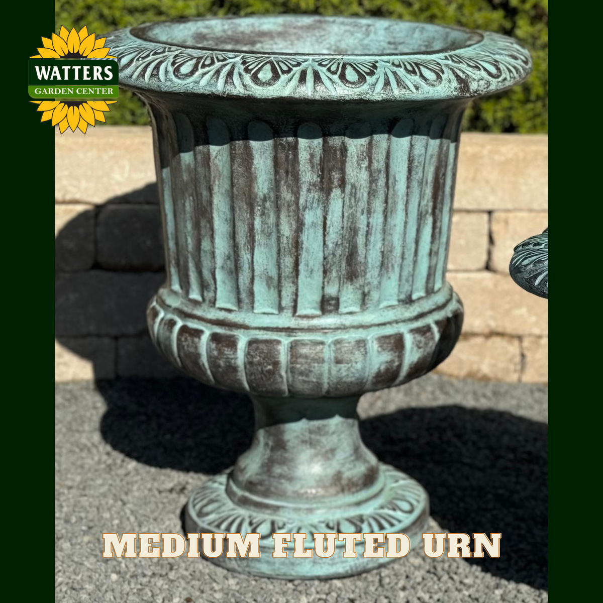 Fluted urn in a garden setting with Watters Branding.