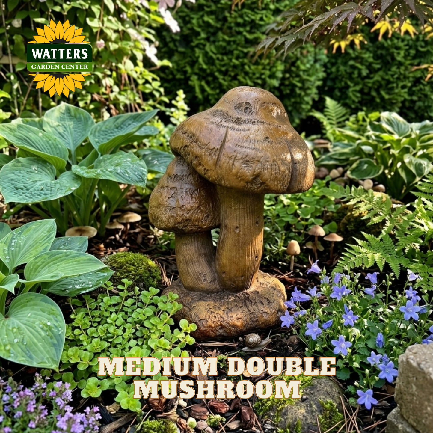 A carved wooden garden statue shaped like two double mushrooms, placed in a lush garden bed surrounded by green foliage, small purple flowers, and mulch. The Watters Gardens Center logo is visible in the top left, and the text 'MEDIUM DOUBLE MUSHROOM' is overlaid at the bottom.