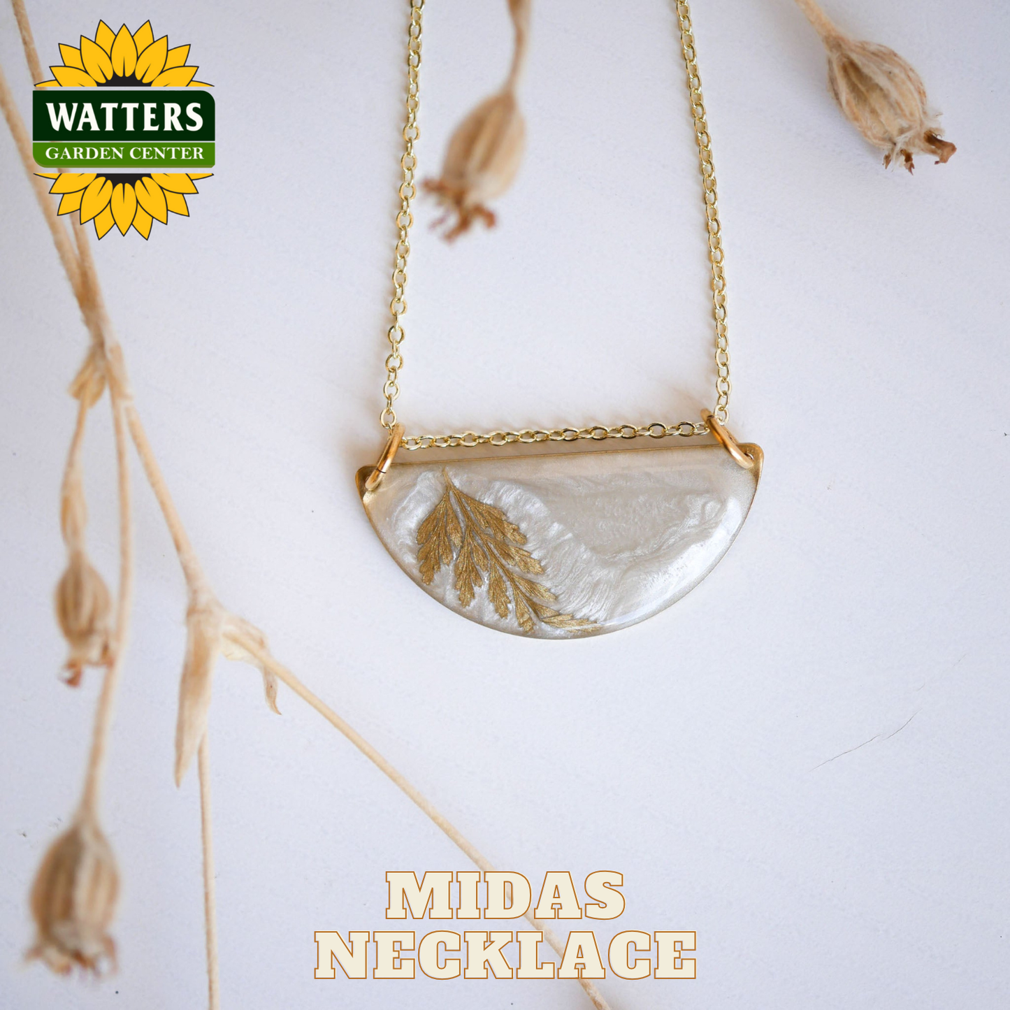 Gold necklace with a half-circle pendant featuring leaf designs on a white background with Watters Garden Center branding.