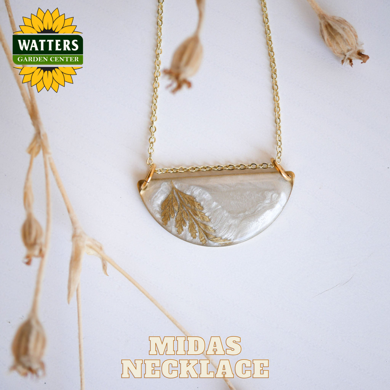 Gold necklace with a half-circle pendant featuring leaf designs on a white background with Watters Garden Center branding.