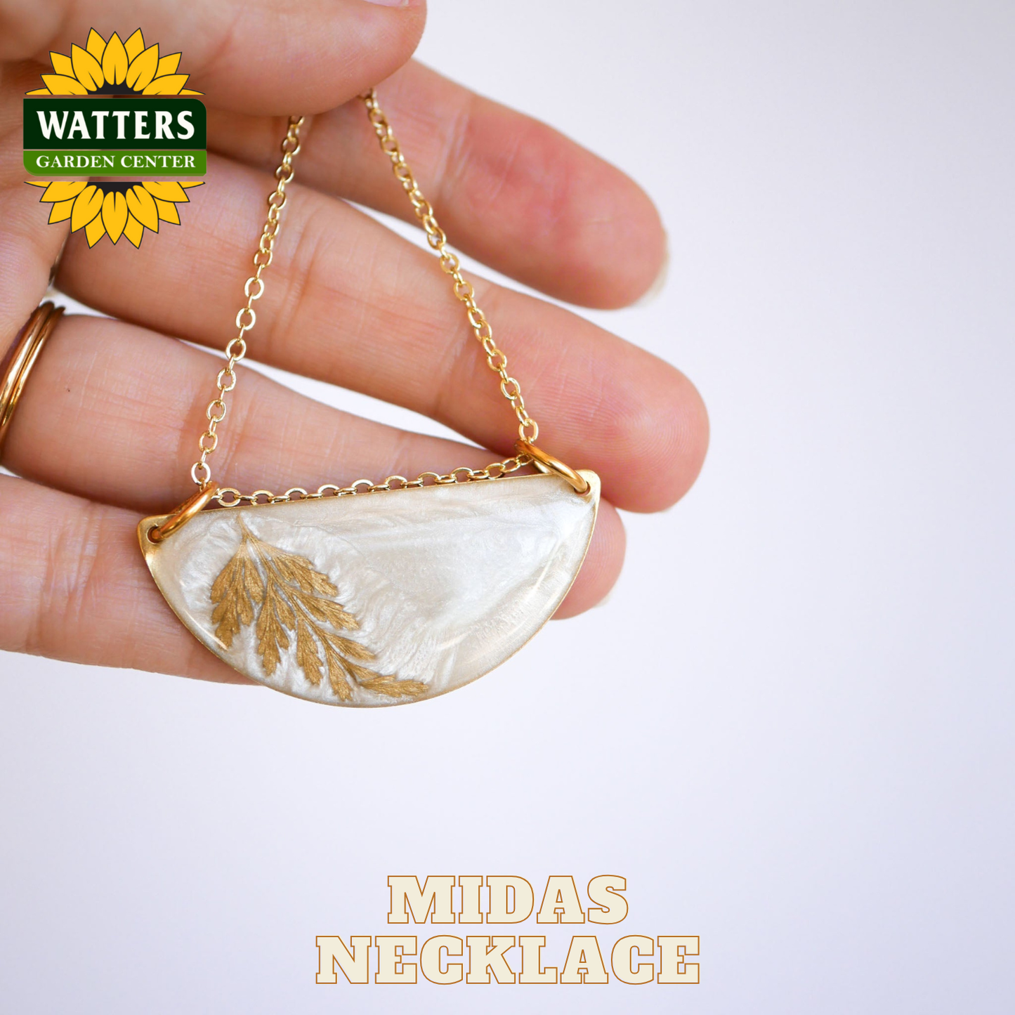 Hand holding a gold and white necklace with 'Watters Garden Center' logo.